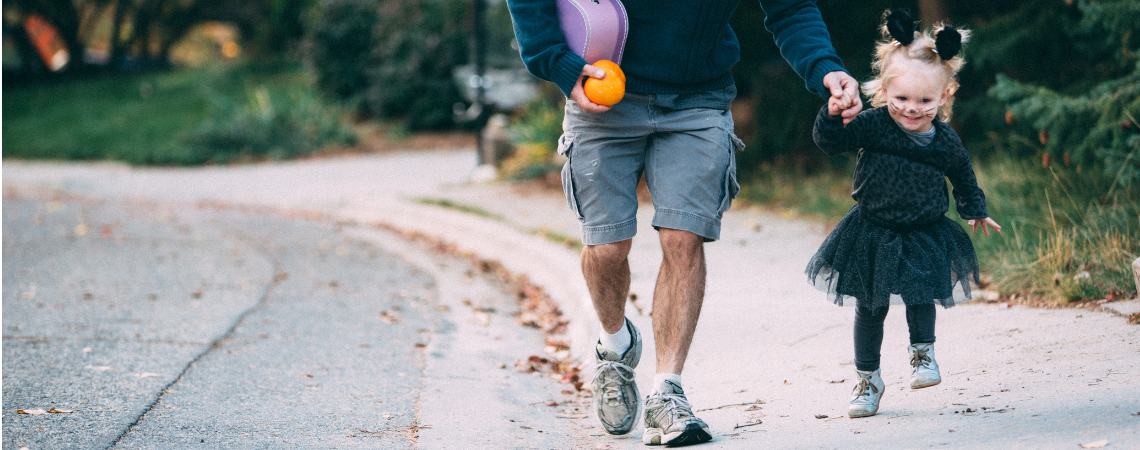 Little girl in cat halloween costume running with dad